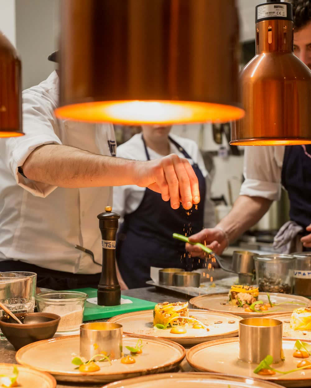 Chefs plating dishes on a restaurant pass